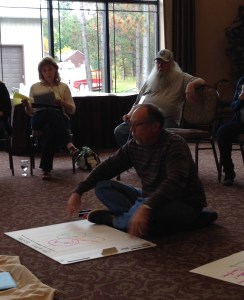 Audrey Moen in the circle with others taking in a teach by Jerry Nagel.